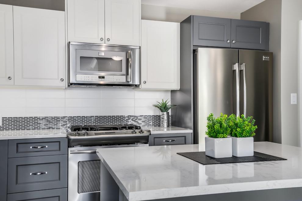 Imagen de cocina minimalista con puertas de armario blancas, electrodomésticos de acero inoxidable y una isla