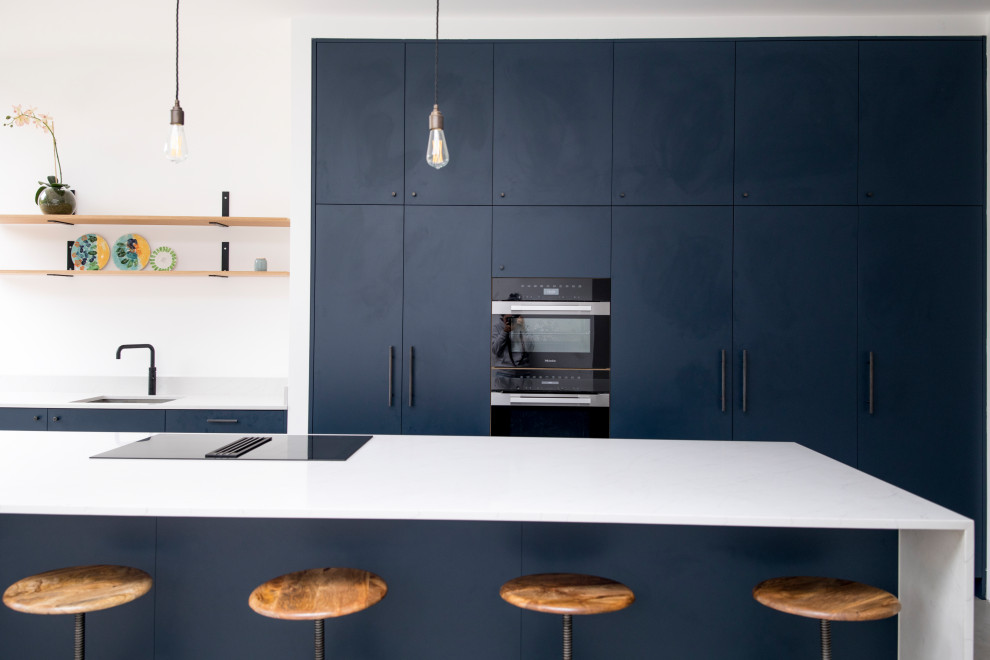 Diseño de cocina minimalista extra grande abierta con fregadero integrado, armarios con paneles lisos, puertas de armario azules, encimera de cuarcita, suelo de azulejos de cemento, una isla, suelo gris y encimeras blancas