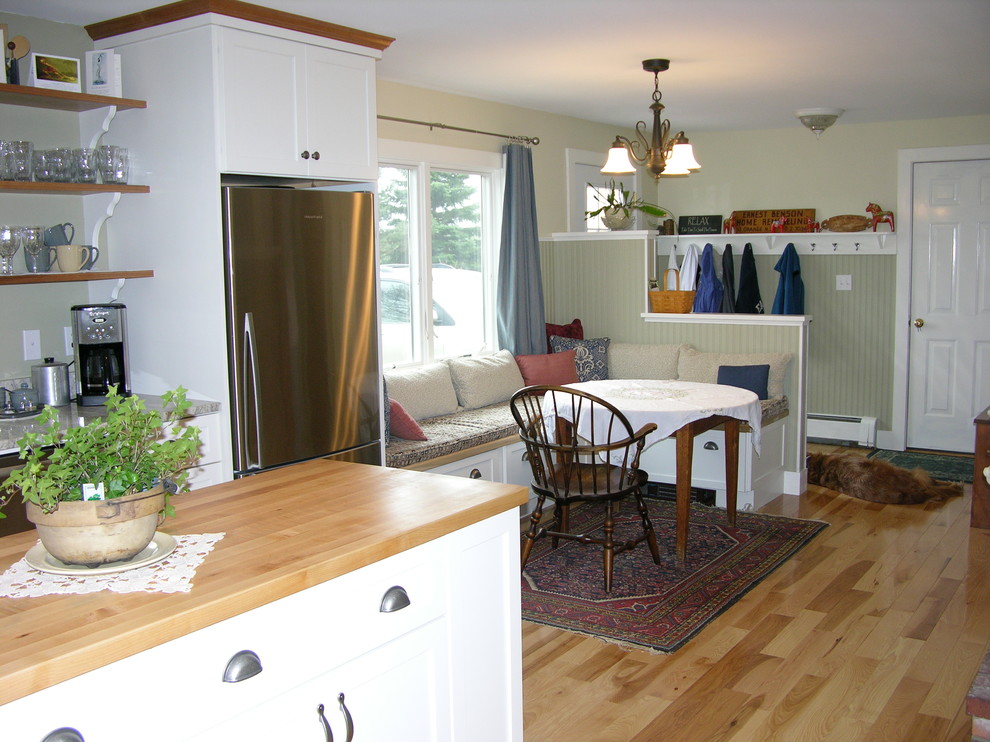 Example of a mid-sized country l-shaped light wood floor eat-in kitchen design in Portland Maine with shaker cabinets, white cabinets, wood countertops, multicolored backsplash, stone slab backsplash, stainless steel appliances and an island