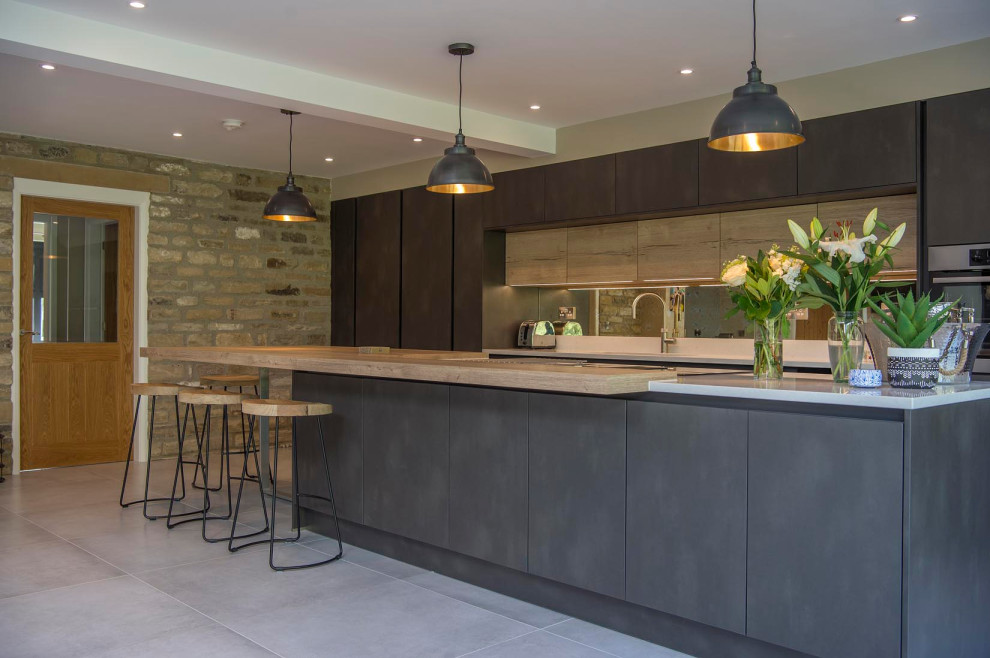 Moderne Küche mit flächenbündigen Schrankfronten, hellen Holzschränken, Arbeitsplatte aus Holz, Keramikboden, Kücheninsel und grauem Boden in Sonstige