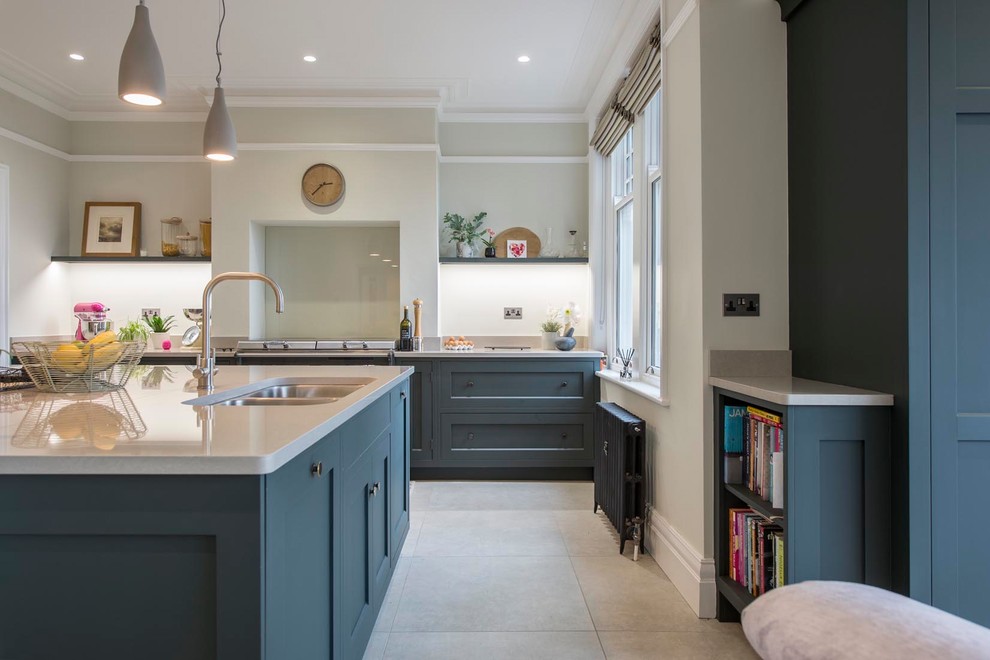 This is an example of a traditional kitchen in Other with a double-bowl sink, shaker cabinets, blue cabinets, glass tiled splashback, an island, beige floors and white worktops.
