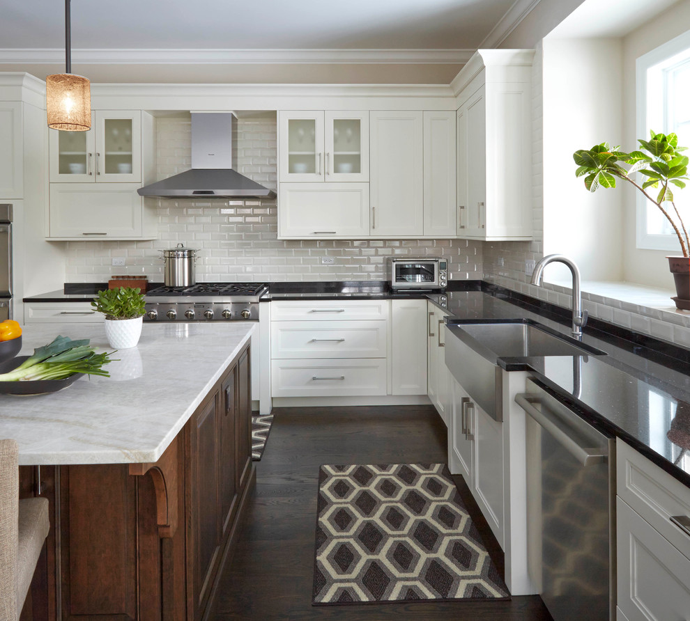 Modern inredning av ett stort kök, med en rustik diskho, luckor med infälld panel, vita skåp, granitbänkskiva, vitt stänkskydd, stänkskydd i tunnelbanekakel, rostfria vitvaror, mellanmörkt trägolv och en köksö