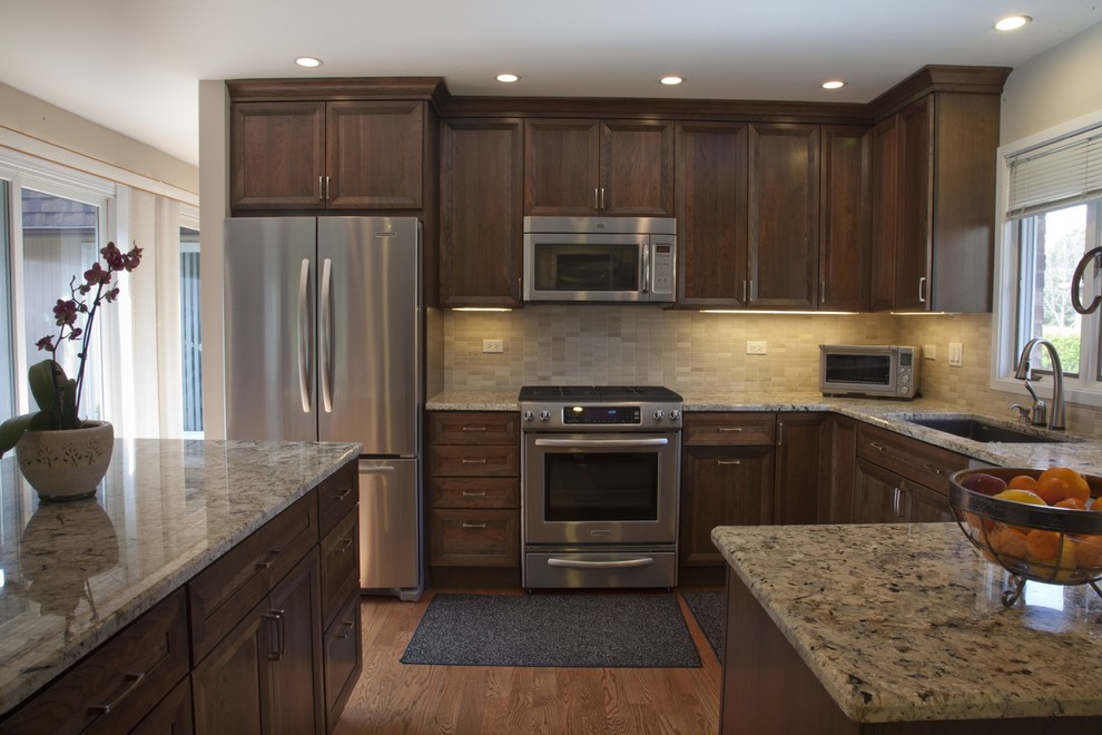 Eat-in kitchen - mid-sized traditional l-shaped medium tone wood floor eat-in kitchen idea in Chicago with an undermount sink, medium tone wood cabinets, granite countertops, beige backsplash, stainless steel appliances and an island
