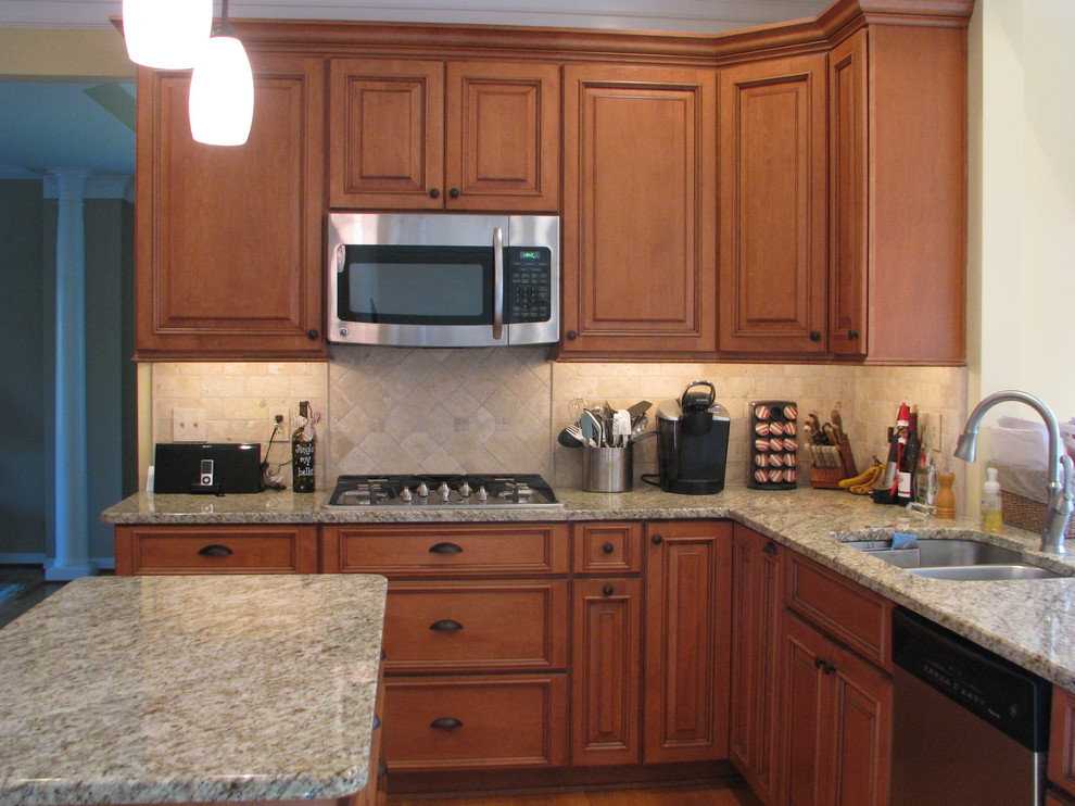 Foto på ett mellanstort vintage kök, med en dubbel diskho, luckor med upphöjd panel, skåp i mellenmörkt trä, granitbänkskiva, beige stänkskydd, stänkskydd i stenkakel, rostfria vitvaror, målat trägolv och en köksö