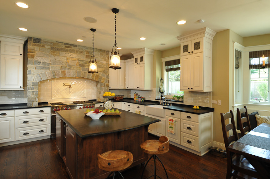 Mountain style l-shaped eat-in kitchen photo in Chicago with a farmhouse sink, raised-panel cabinets, white cabinets, soapstone countertops, white backsplash, subway tile backsplash and paneled appliances