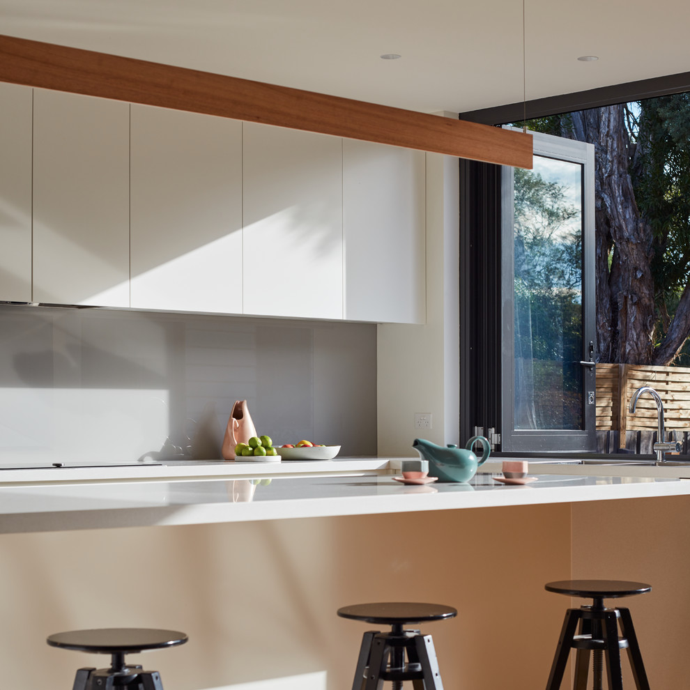 Immagine di una cucina design con lavello a doppia vasca, paraspruzzi grigio, paraspruzzi con lastra di vetro e parquet chiaro
