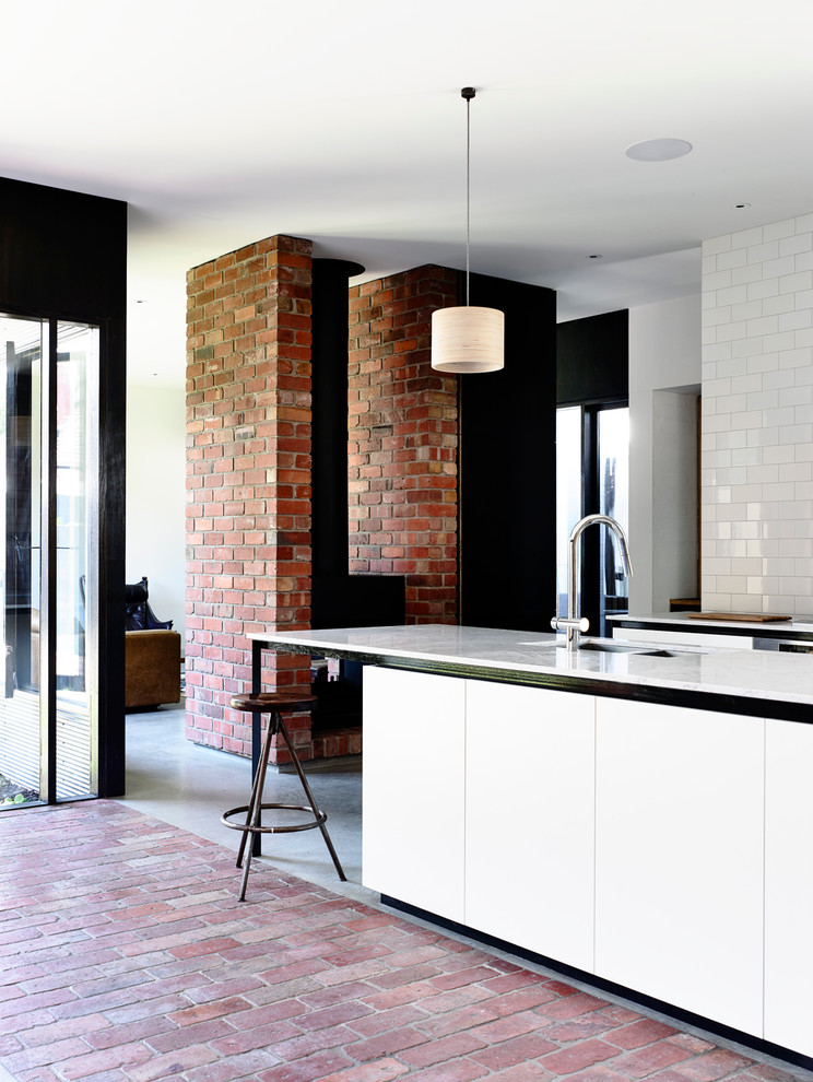 Exempel på ett mellanstort modernt kök, med en undermonterad diskho, släta luckor, vita skåp, bänkskiva i kvarts, vitt stänkskydd, stänkskydd i tunnelbanekakel, rostfria vitvaror, betonggolv och en köksö