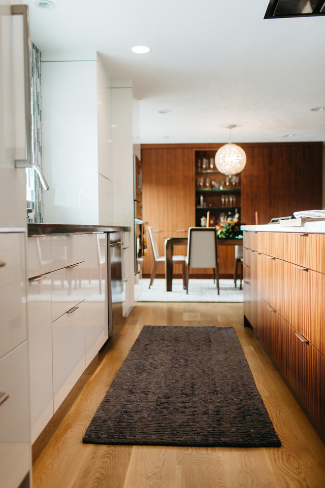 Mid-sized trendy galley light wood floor open concept kitchen photo in Seattle with an undermount sink, flat-panel cabinets, white cabinets, marble countertops, multicolored backsplash, matchstick tile backsplash, stainless steel appliances and an island