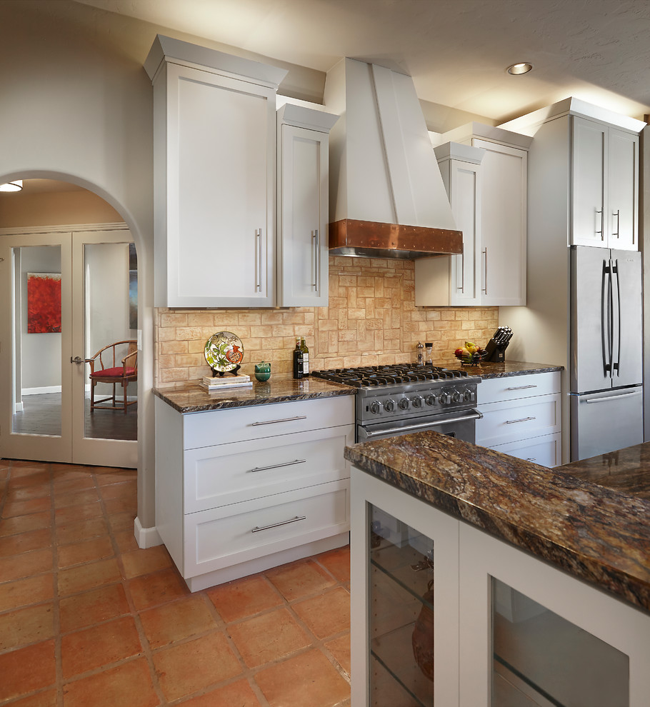 Photo of a traditional kitchen in Phoenix with a double-bowl sink, shaker cabinets, white cabinets, granite worktops, beige splashback, stone tiled splashback, stainless steel appliances and terracotta flooring.