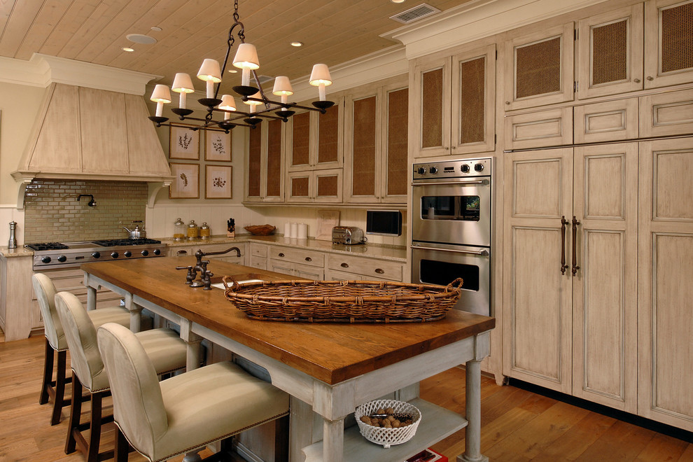 Klassisk inredning av ett kök, med luckor med infälld panel, rostfria vitvaror, en köksö, en undermonterad diskho, skåp i ljust trä, grönt stänkskydd, stänkskydd i tunnelbanekakel och mellanmörkt trägolv