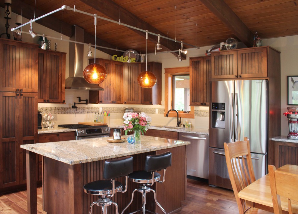 Photo of a medium sized rustic l-shaped kitchen/diner in Other with a built-in sink, dark wood cabinets, granite worktops, beige splashback, stainless steel appliances, light hardwood flooring and an island.