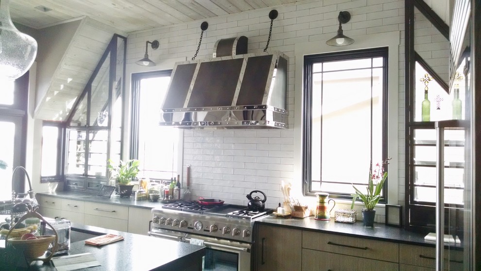 Exempel på ett avskilt, mellanstort industriellt svart svart l-kök, med en undermonterad diskho, släta luckor, bruna skåp, granitbänkskiva, vitt stänkskydd, stänkskydd i cementkakel, rostfria vitvaror, mellanmörkt trägolv, en köksö och beiget golv