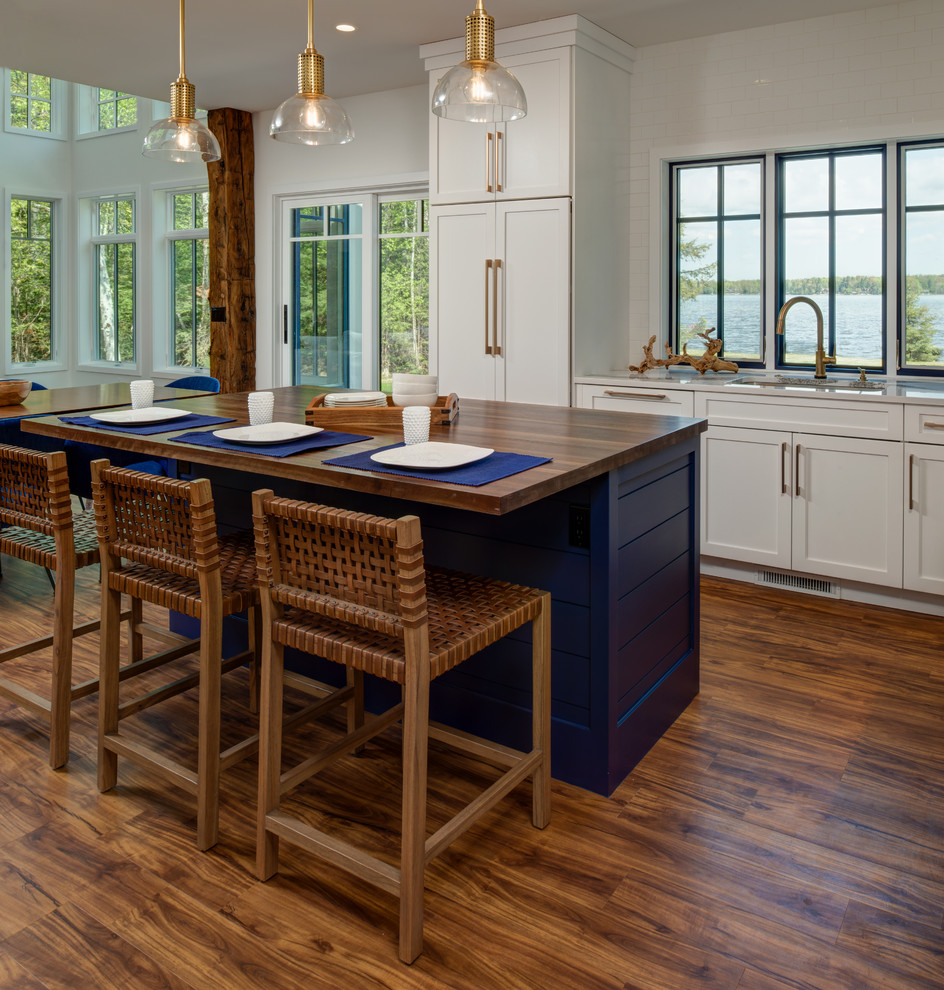 Inspiration for a mid-sized transitional l-shaped medium tone wood floor and brown floor eat-in kitchen remodel in Other with an undermount sink, shaker cabinets, white cabinets, quartz countertops, blue backsplash, glass tile backsplash, paneled appliances, an island and white countertops