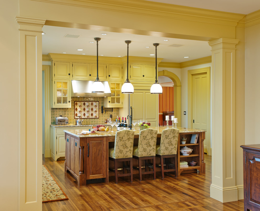 Bild på ett stort vintage l-kök, med en köksö, luckor med upphöjd panel, gula skåp, granitbänkskiva, flerfärgad stänkskydd, stänkskydd i keramik, integrerade vitvaror, mellanmörkt trägolv och en rustik diskho