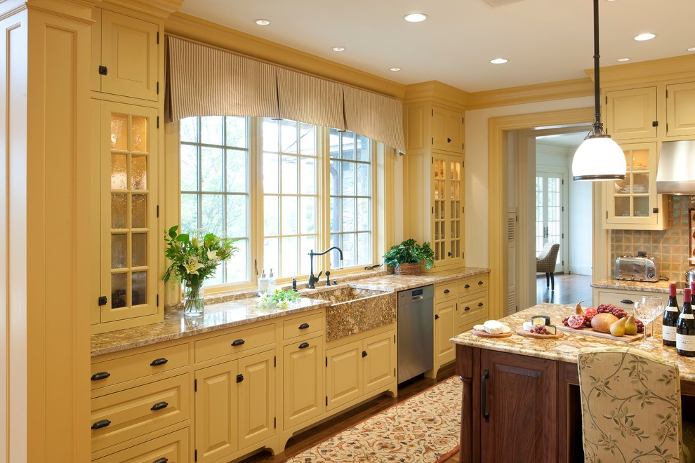 Große Klassische Küche in L-Form mit Landhausspüle, profilierten Schrankfronten, gelben Schränken, Granit-Arbeitsplatte, bunter Rückwand, Rückwand aus Keramikfliesen, Küchengeräten aus Edelstahl, braunem Holzboden und Kücheninsel in Sonstige
