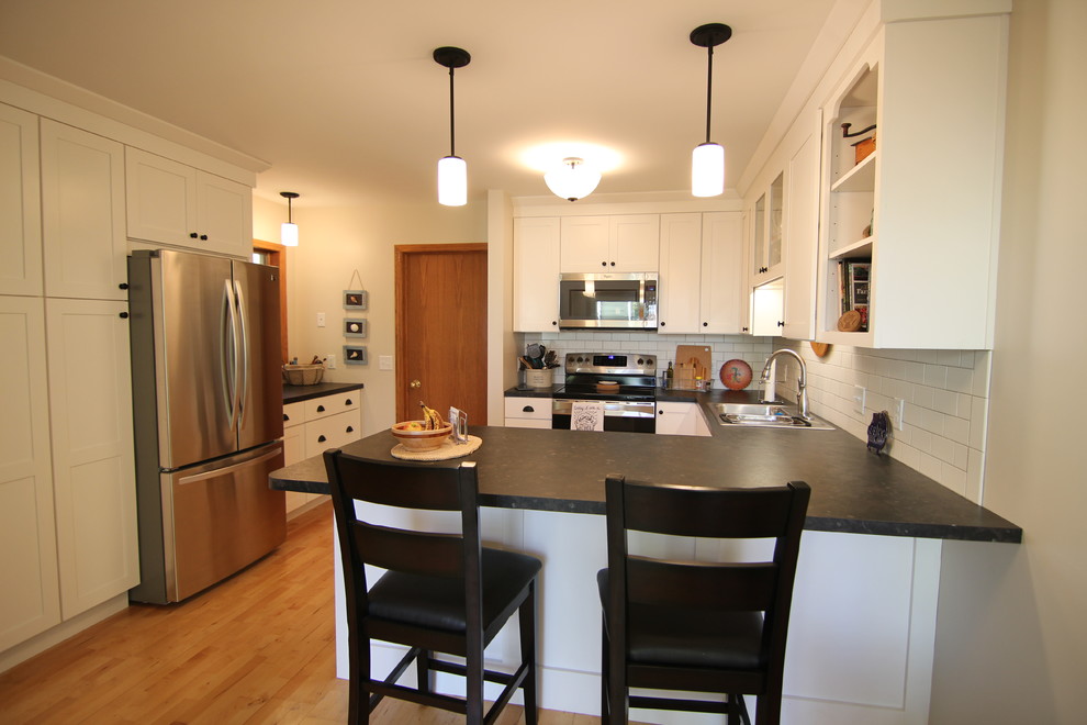Bild på ett litet lantligt kök, med en nedsänkt diskho, skåp i shakerstil, vita skåp, laminatbänkskiva, vitt stänkskydd, stänkskydd i keramik, rostfria vitvaror, ljust trägolv och en halv köksö