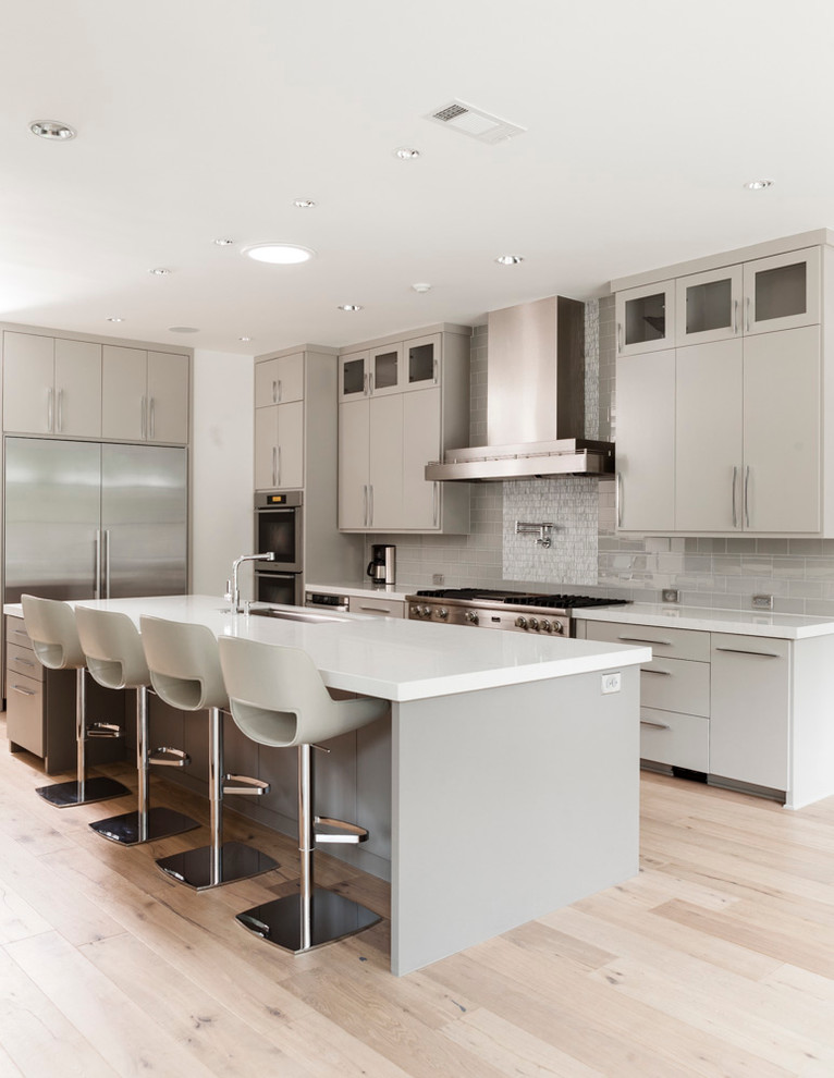 This is an example of a contemporary grey and white l-shaped kitchen in Dallas with flat-panel cabinets, grey cabinets, grey splashback and stainless steel appliances.