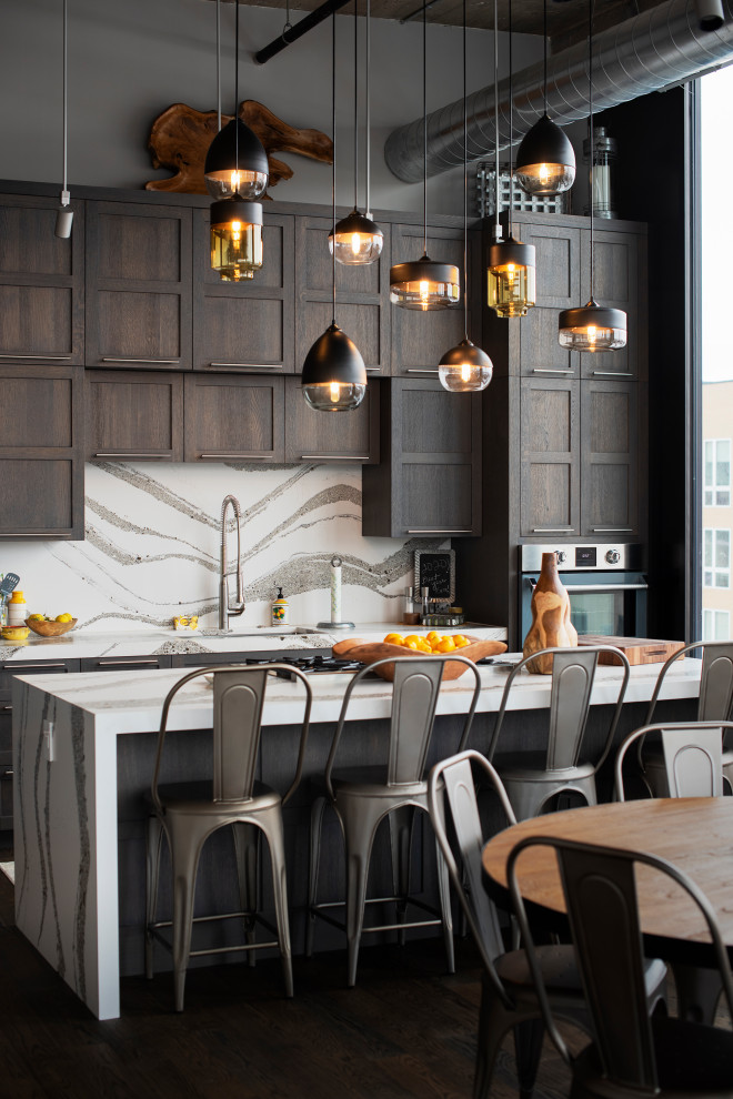 Immagine di una cucina industriale con lavello sottopiano, ante in stile shaker, ante in legno bruno, paraspruzzi bianco, elettrodomestici in acciaio inossidabile, parquet scuro, pavimento marrone e top bianco
