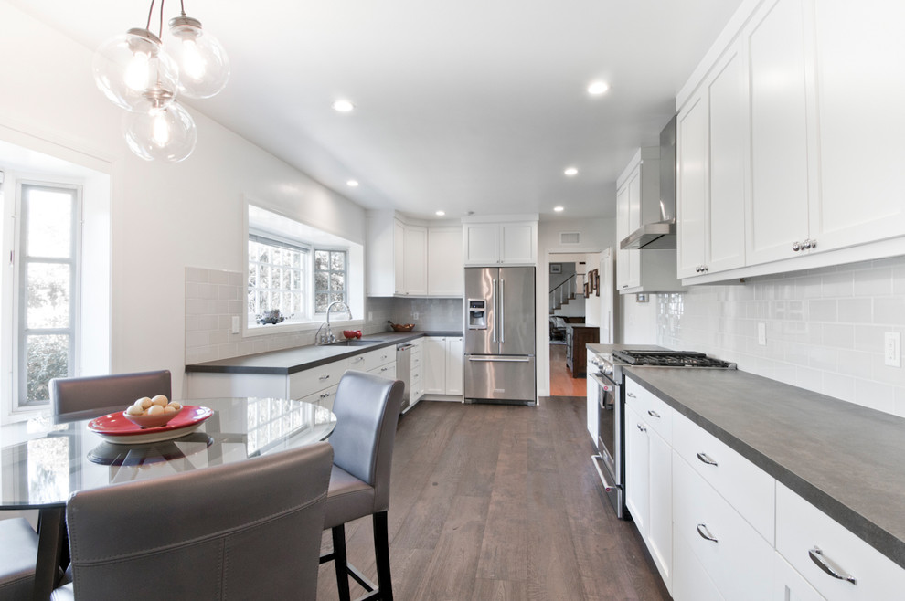 This is an example of a medium sized traditional u-shaped kitchen/diner in Los Angeles with a submerged sink, shaker cabinets, white cabinets, quartz worktops, white splashback, ceramic splashback, stainless steel appliances, medium hardwood flooring, no island and brown floors.
