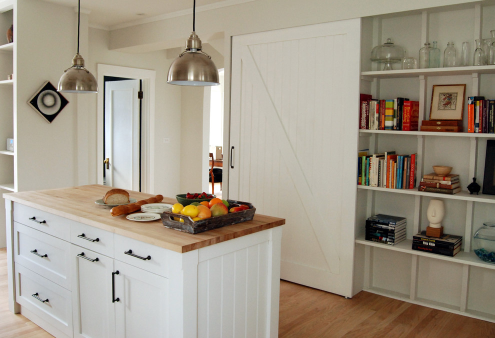 Cette image montre une cuisine rustique avec un plan de travail en bois, un placard sans porte et des portes de placard blanches.