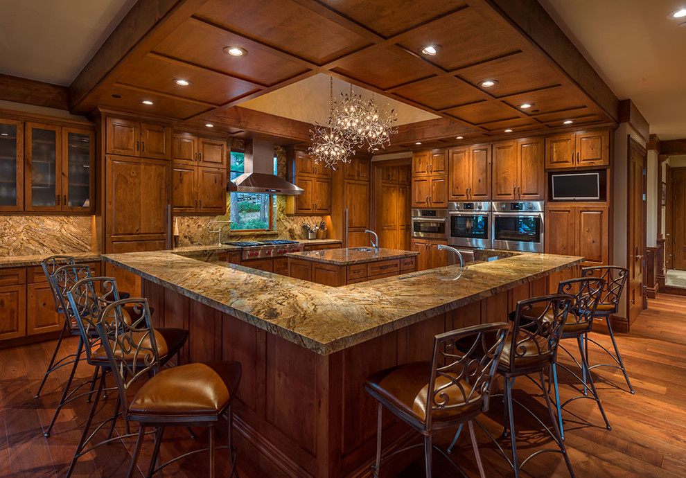 Photo of a rustic kitchen in Sacramento with a submerged sink, raised-panel cabinets, medium wood cabinets, multi-coloured splashback, stainless steel appliances, medium hardwood flooring, multiple islands and brown floors.