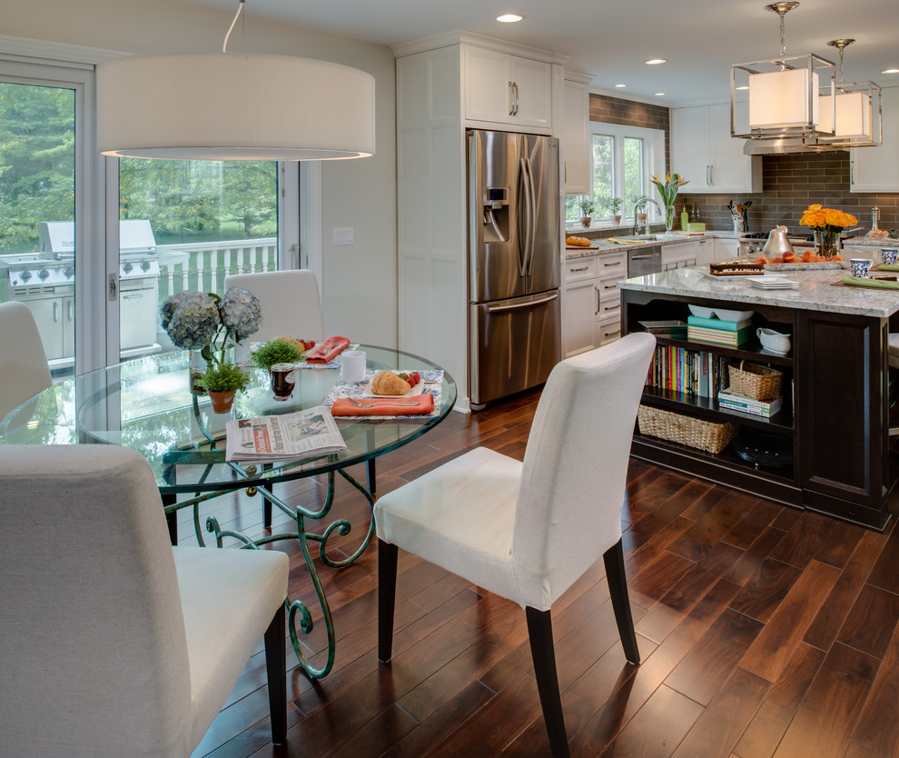 Example of a mid-sized transitional l-shaped dark wood floor eat-in kitchen design in Detroit with an undermount sink, recessed-panel cabinets, white cabinets, granite countertops, gray backsplash, stone tile backsplash, stainless steel appliances and an island