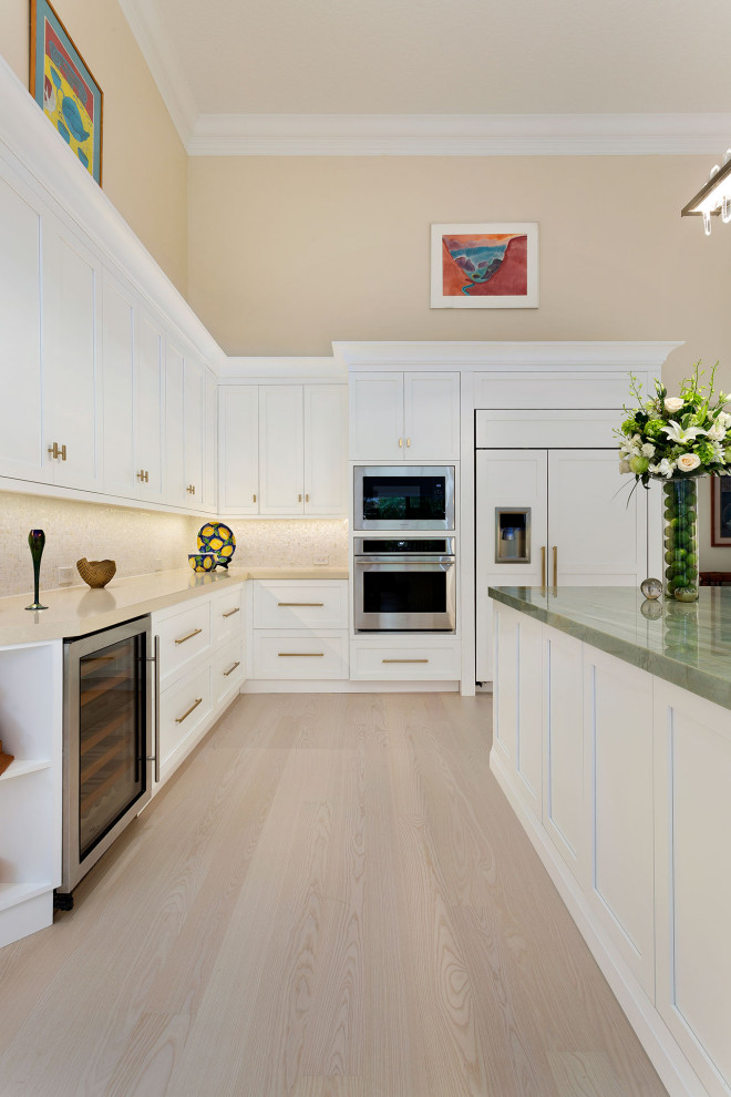 Inredning av ett klassiskt mellanstort grön grönt kök, med en undermonterad diskho, skåp i shakerstil, vita skåp, marmorbänkskiva, beige stänkskydd, stänkskydd i mosaik, rostfria vitvaror, ljust trägolv, en köksö och beiget golv