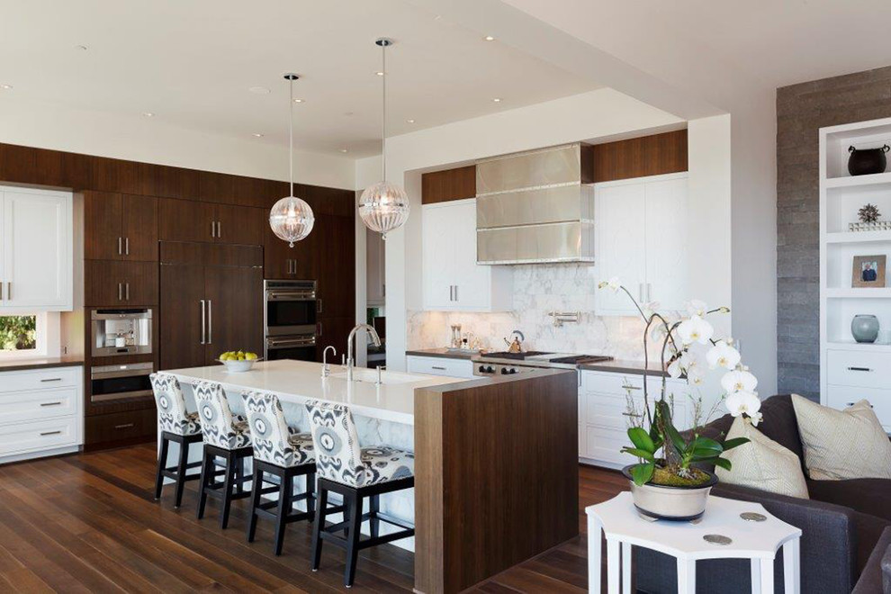 Cette image montre une cuisine ouverte encastrable design en L et bois foncé avec un placard à porte plane, un plan de travail en quartz et une crédence blanche.