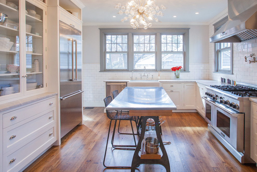 Example of a transitional l-shaped dark wood floor enclosed kitchen design in DC Metro with a farmhouse sink, beaded inset cabinets, white cabinets, marble countertops, subway tile backsplash, white backsplash and stainless steel appliances