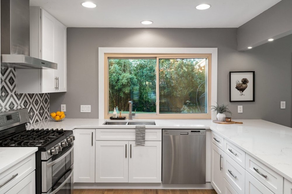 Eat-in kitchen - large modern u-shaped light wood floor and brown floor eat-in kitchen idea in Austin with a double-bowl sink, shaker cabinets, white cabinets, quartz countertops, multicolored backsplash, porcelain backsplash, stainless steel appliances, no island and white countertops