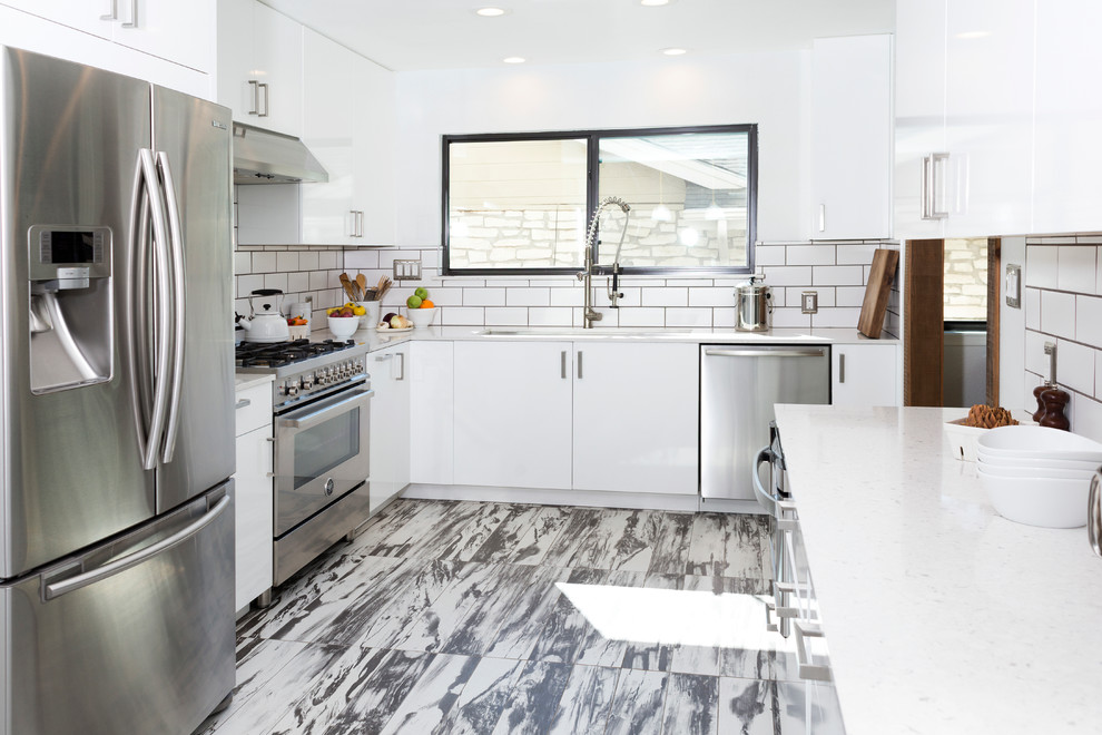 Inspiration for a medium sized contemporary l-shaped enclosed kitchen in Dallas with flat-panel cabinets, white splashback, stainless steel appliances, a submerged sink, white cabinets, quartz worktops, metro tiled splashback, porcelain flooring and an island.
