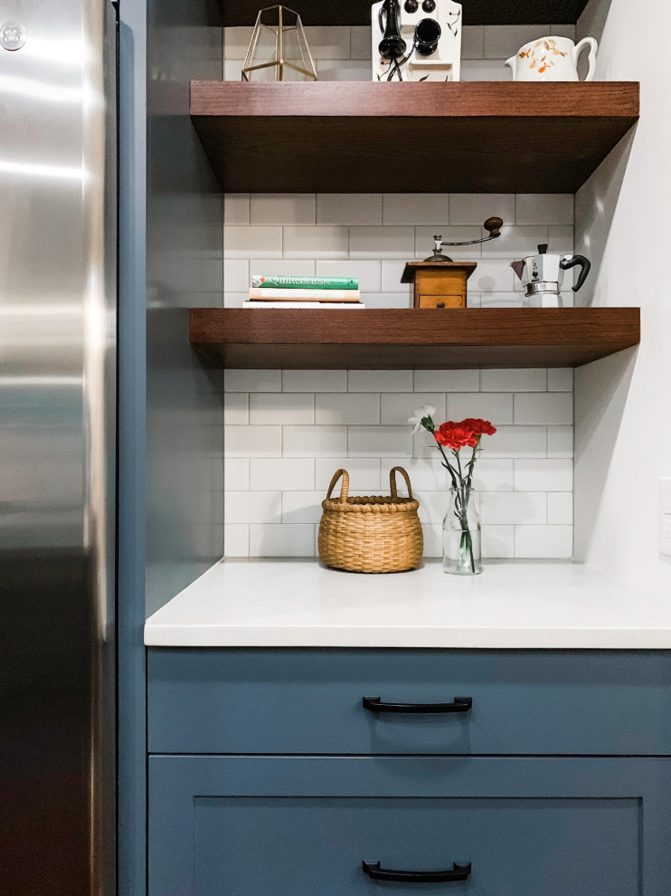 This is an example of a small classic u-shaped kitchen/diner in Austin with a double-bowl sink, shaker cabinets, blue cabinets, engineered stone countertops, white splashback, metro tiled splashback, stainless steel appliances, dark hardwood flooring, an island, brown floors and white worktops.