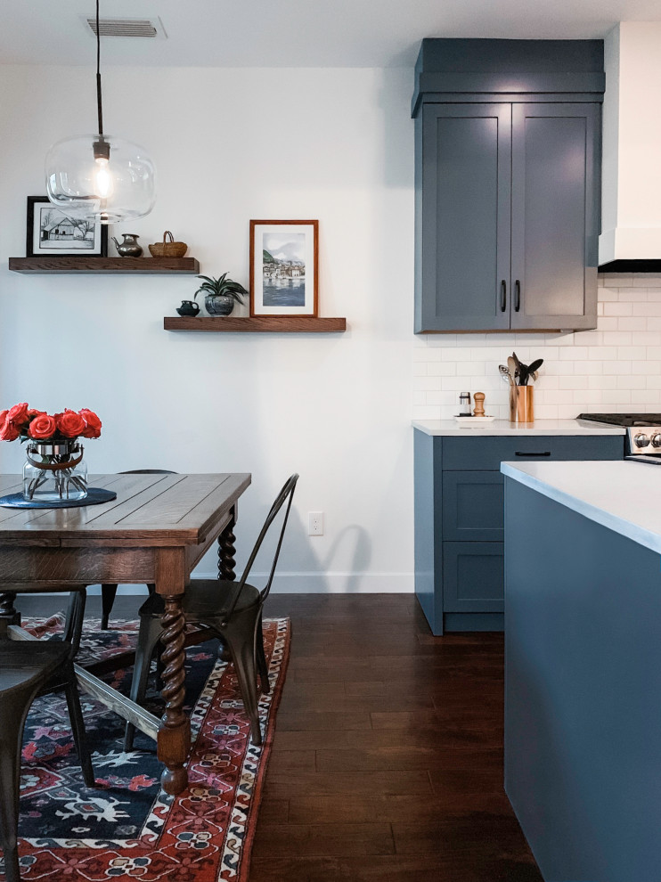 Small transitional u-shaped dark wood floor and brown floor eat-in kitchen photo in Austin with a double-bowl sink, shaker cabinets, blue cabinets, quartz countertops, white backsplash, subway tile backsplash, stainless steel appliances, an island and white countertops