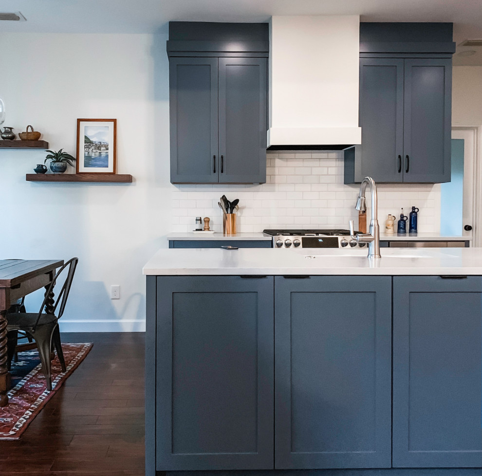 Small transitional u-shaped dark wood floor and brown floor eat-in kitchen photo in Austin with a double-bowl sink, shaker cabinets, blue cabinets, quartz countertops, white backsplash, subway tile backsplash, stainless steel appliances, an island and white countertops