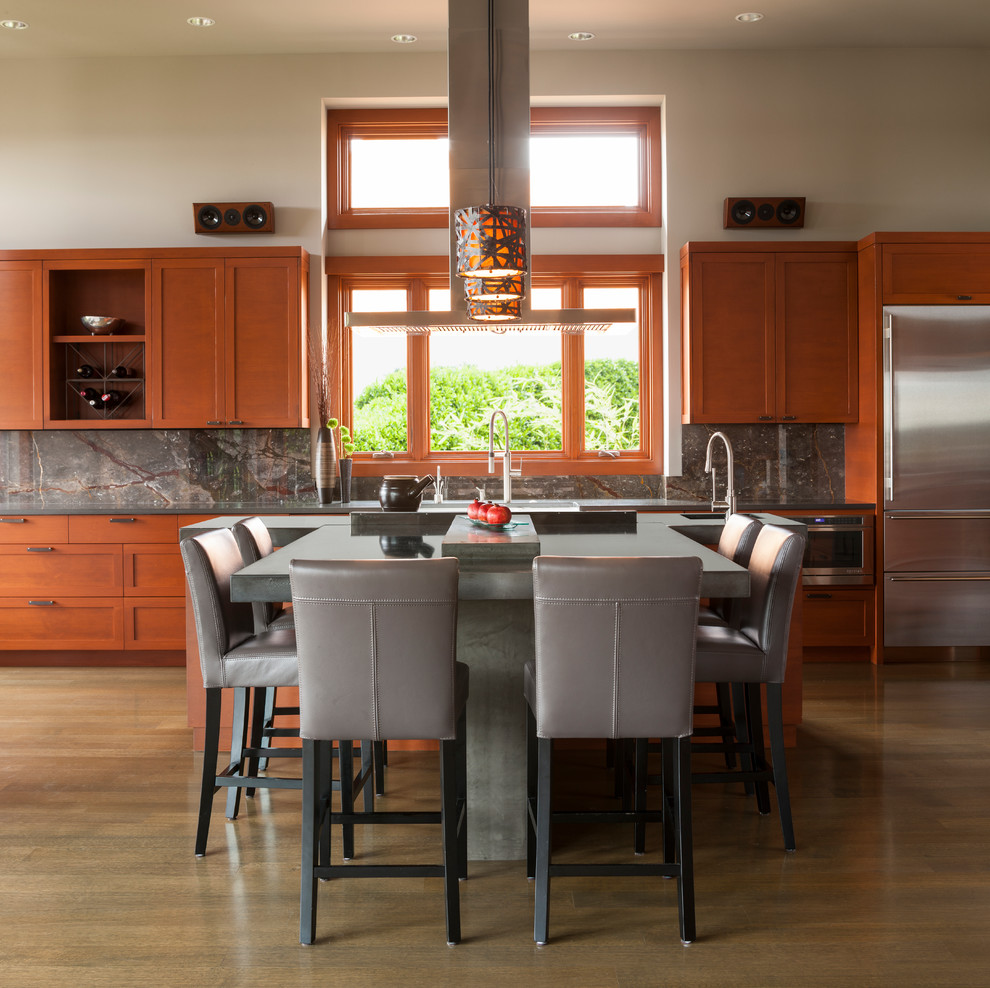 Cette photo montre une cuisine tendance en bois brun avec un placard à porte shaker, une crédence grise, une crédence en dalle de pierre et un électroménager en acier inoxydable.