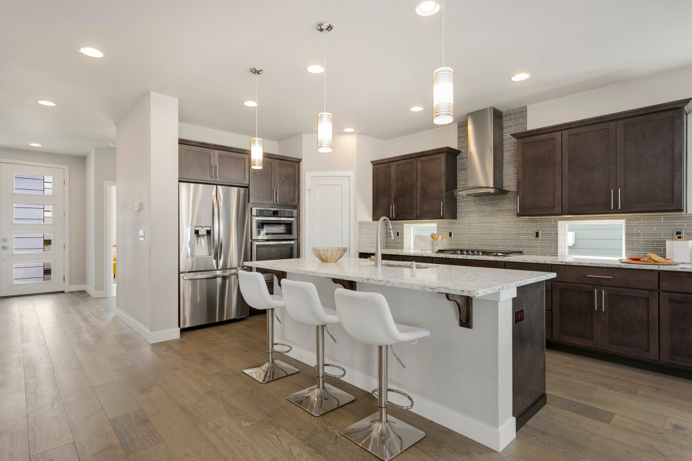 Inspiration for a large contemporary l-shaped medium tone wood floor and brown floor eat-in kitchen remodel in Seattle with a drop-in sink, dark wood cabinets, gray backsplash, glass tile backsplash, stainless steel appliances, an island and multicolored countertops