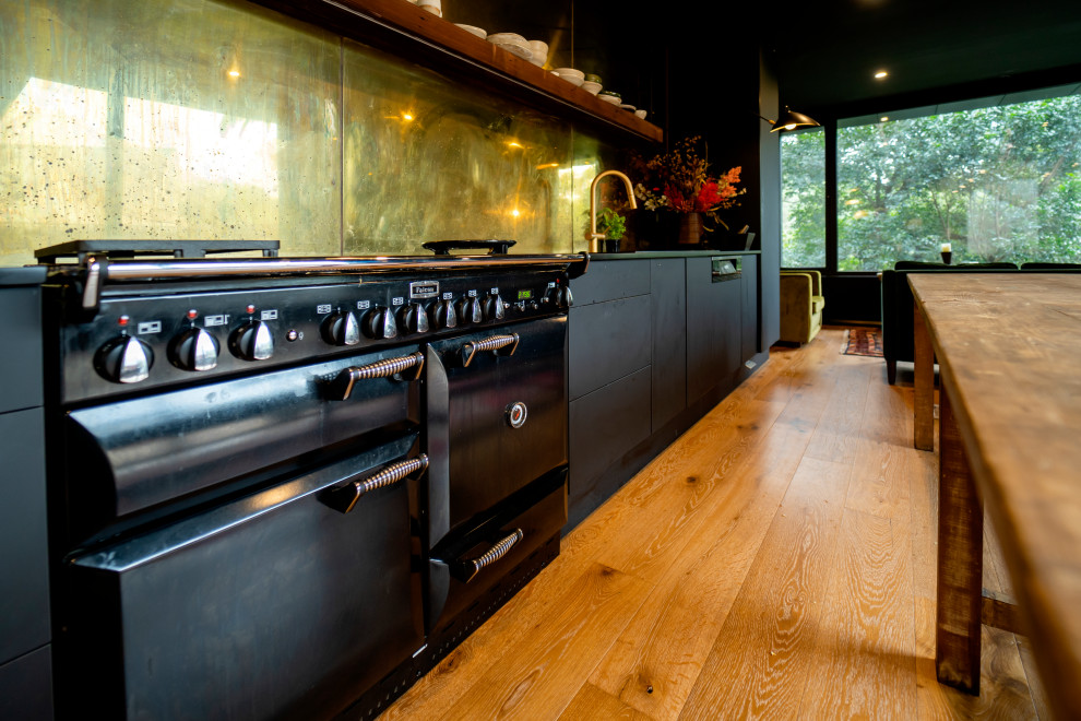 シドニーにある広いアジアンスタイルのおしゃれなキッチン (ドロップインシンク、フラットパネル扉のキャビネット、黒いキャビネット、クオーツストーンカウンター、メタリックのキッチンパネル、メタルタイルのキッチンパネル、黒い調理設備、淡色無垢フローリング、茶色い床、黒いキッチンカウンター) の写真