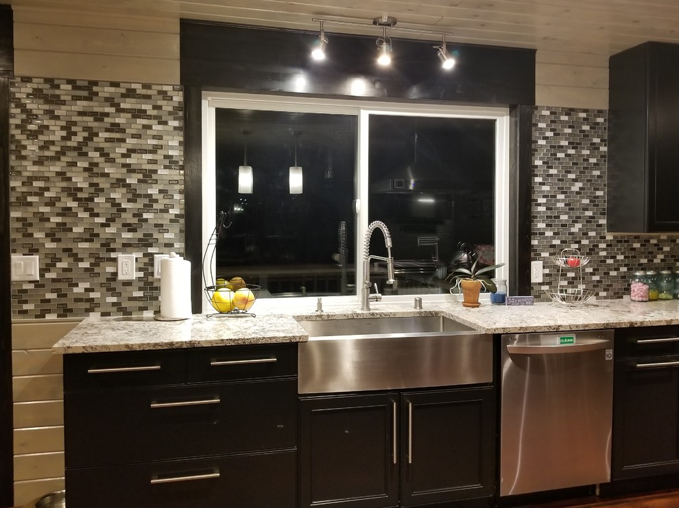 Country l-shaped dark wood floor open concept kitchen photo in Minneapolis with a farmhouse sink, recessed-panel cabinets, black cabinets, granite countertops, gray backsplash, mosaic tile backsplash, stainless steel appliances and an island