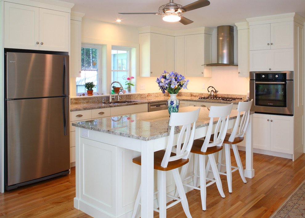 Example of a mid-sized transitional l-shaped light wood floor and beige floor eat-in kitchen design in Portland Maine with a double-bowl sink, shaker cabinets, white cabinets, granite countertops, multicolored backsplash, stone slab backsplash, stainless steel appliances and an island