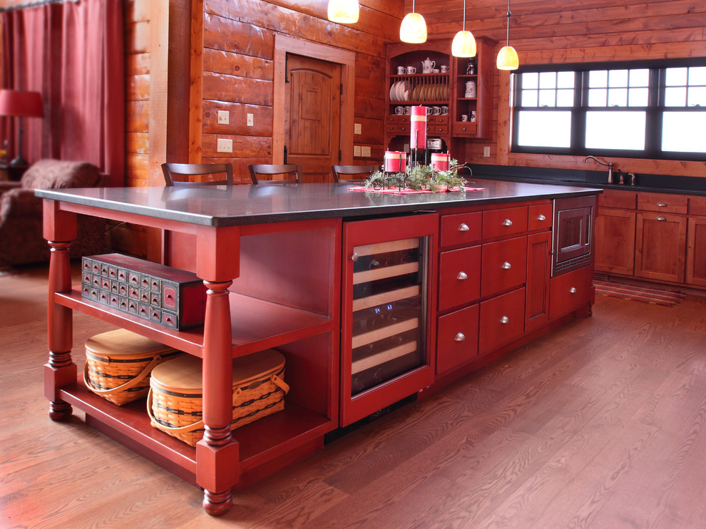 Large rustic l-shaped open plan kitchen in Minneapolis with a submerged sink, flat-panel cabinets, red cabinets, granite worktops, black splashback, stainless steel appliances, medium hardwood flooring and an island.