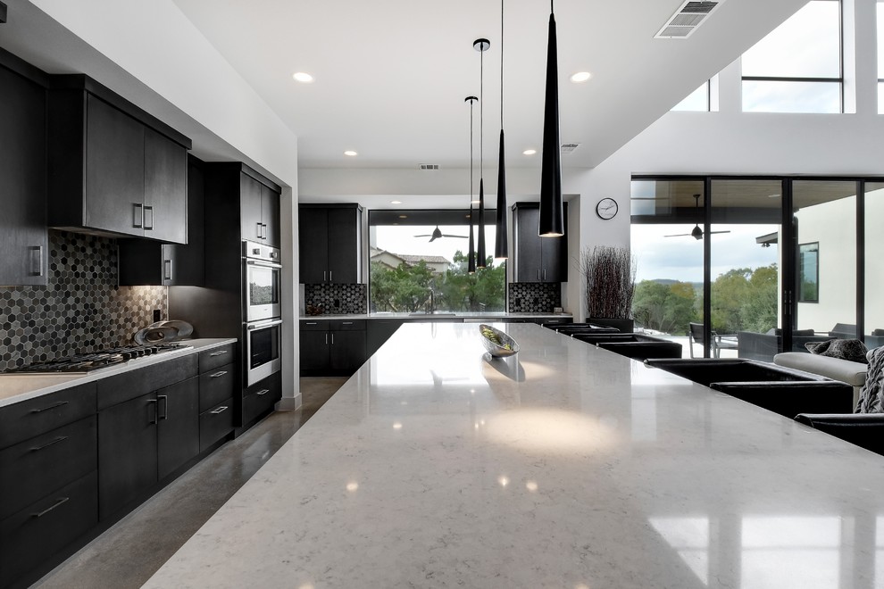 Large trendy u-shaped concrete floor and gray floor open concept kitchen photo in Austin with an undermount sink, flat-panel cabinets, dark wood cabinets, quartz countertops, multicolored backsplash, mosaic tile backsplash, stainless steel appliances, an island and white countertops