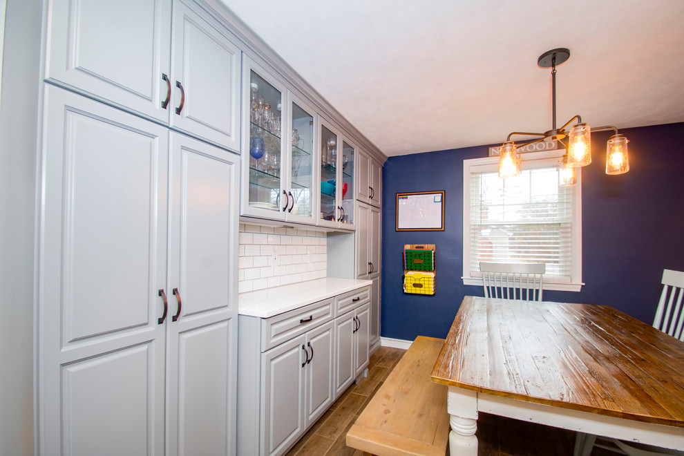 Inredning av ett vit vitt kök och matrum, med en rustik diskho, grå skåp, flerfärgad stänkskydd, stänkskydd i tunnelbanekakel, rostfria vitvaror, mellanmörkt trägolv, en köksö och brunt golv