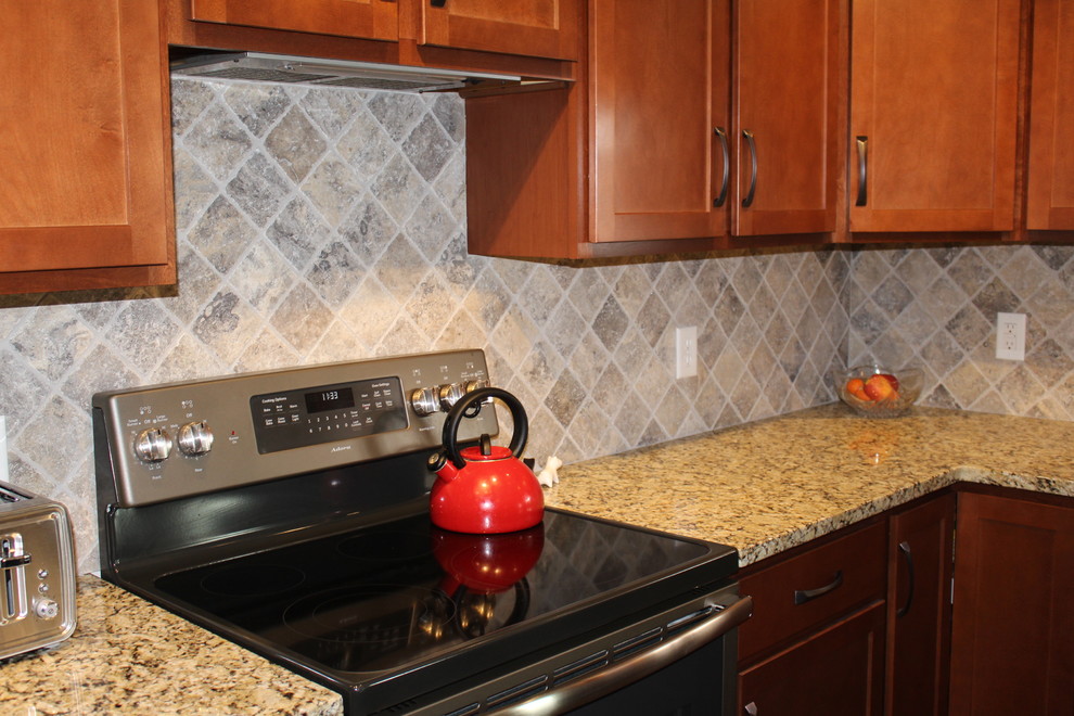 Exempel på ett klassiskt kök, med en rustik diskho, luckor med infälld panel, skåp i ljust trä, granitbänkskiva, grått stänkskydd, stänkskydd i travertin, vinylgolv, en köksö och brunt golv