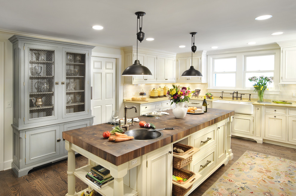 Example of a classic kitchen design in Chicago with stainless steel appliances, a farmhouse sink and wood countertops