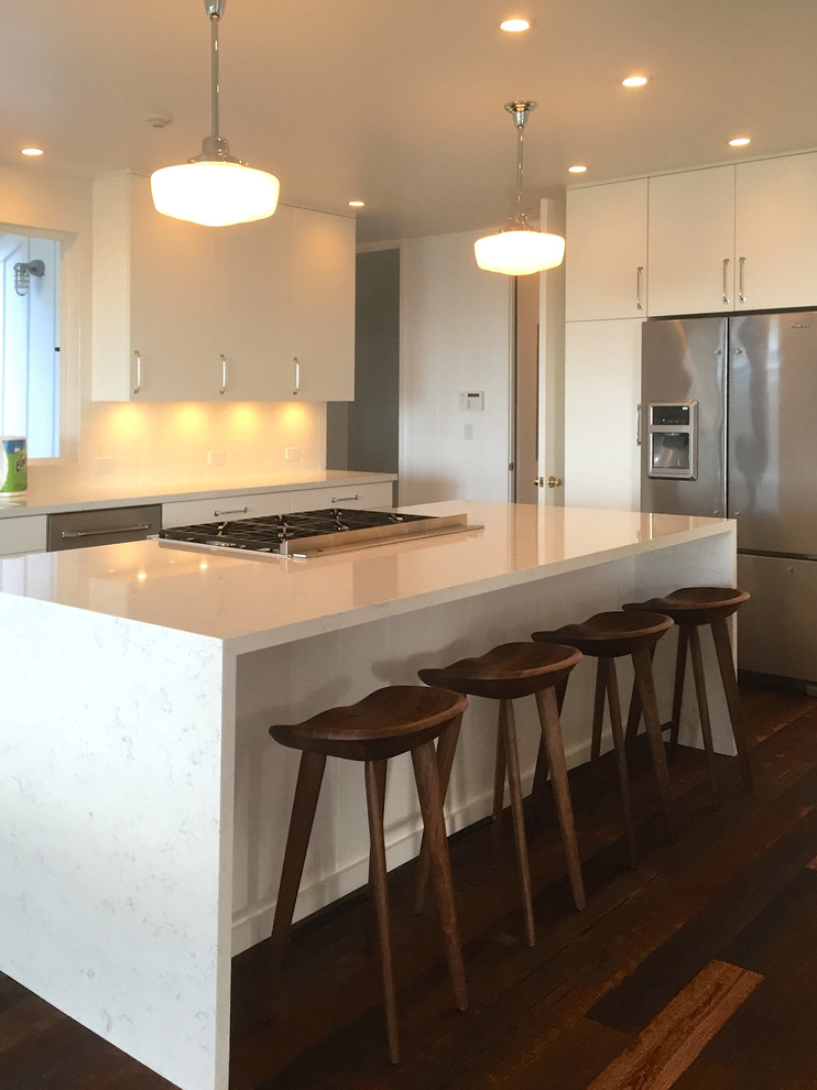 Exempel på ett mellanstort modernt kök, med en undermonterad diskho, släta luckor, vita skåp, bänkskiva i kvarts, vitt stänkskydd, stänkskydd i keramik, rostfria vitvaror, mörkt trägolv, en köksö och brunt golv