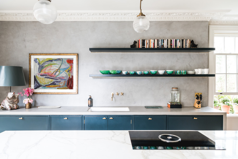 Aménagement d'une cuisine parallèle et encastrable classique avec un évier 1 bac, un placard à porte plane, des portes de placard bleues, une crédence grise, îlot et un plan de travail gris.