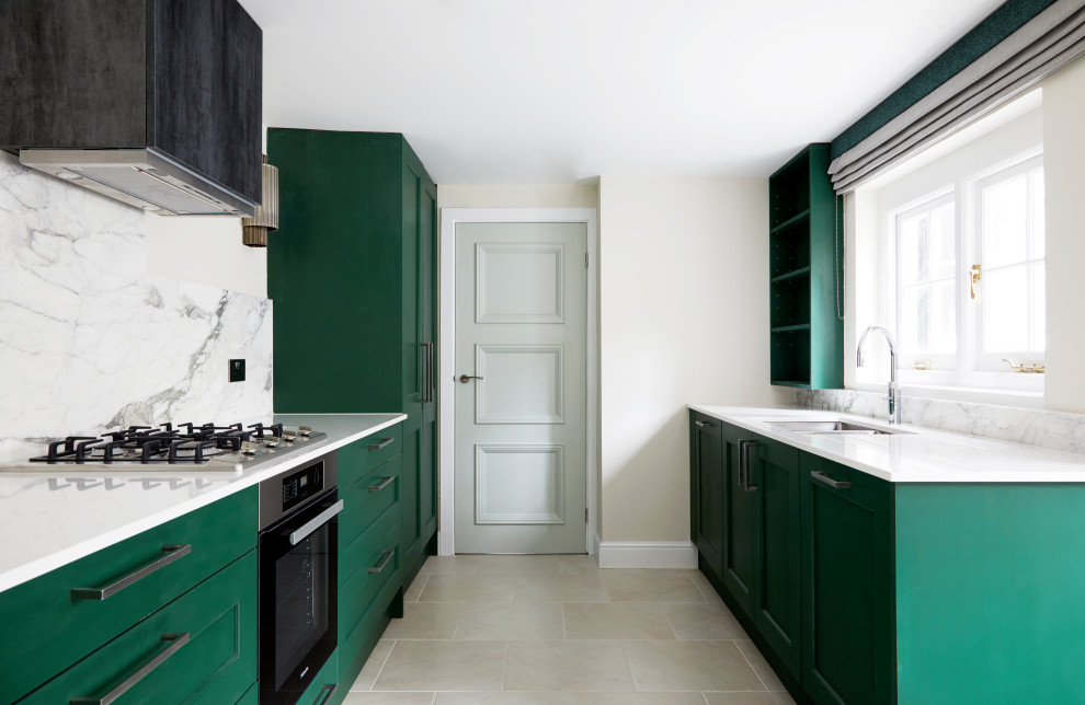 Design ideas for a medium sized traditional galley enclosed kitchen in London with a double-bowl sink, recessed-panel cabinets, green cabinets, composite countertops, grey splashback, porcelain splashback, stainless steel appliances, porcelain flooring, no island, beige floors and white worktops.