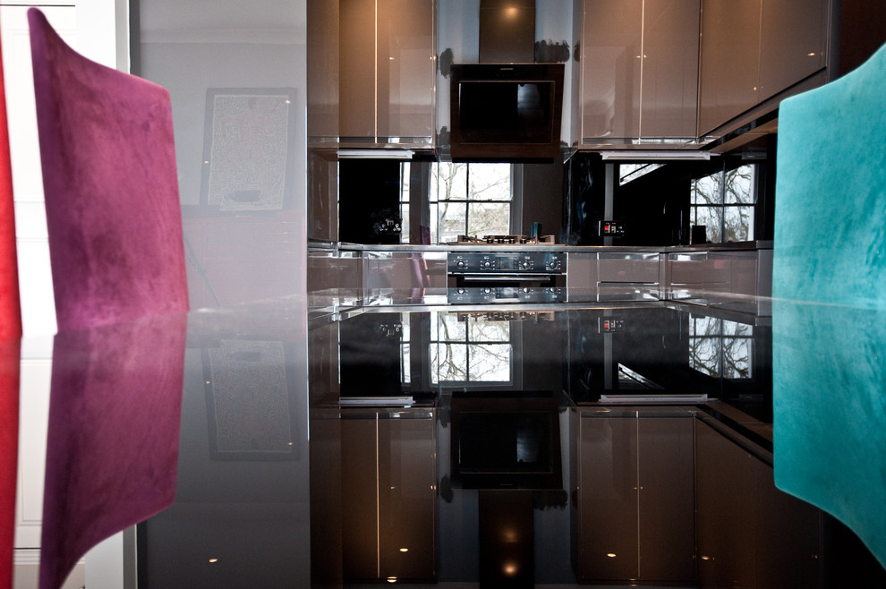 Immagine di una cucina design di medie dimensioni con lavello da incasso, ante lisce, ante grigie, elettrodomestici neri, nessuna isola, paraspruzzi nero, top in granito, paraspruzzi con lastra di vetro e pavimento in legno massello medio