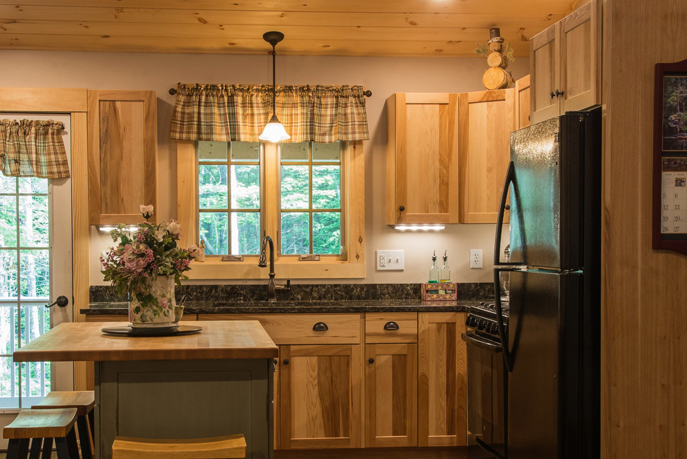 Country medium tone wood floor kitchen photo in Manchester with shaker cabinets, an undermount sink, medium tone wood cabinets, quartz countertops, black appliances and an island