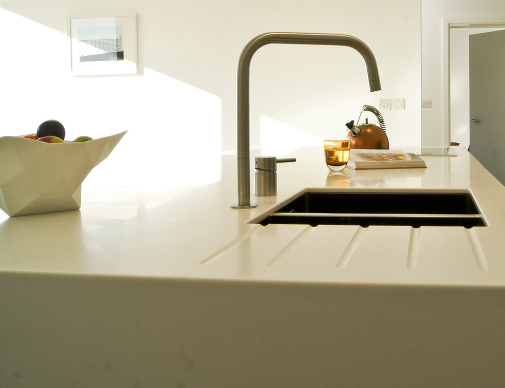Foto di una cucina design di medie dimensioni con lavello sottopiano, ante lisce, ante bianche, top in vetro, elettrodomestici neri e pavimento in ardesia
